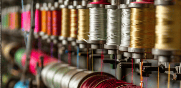 Bobines de fil colorées exposées en vitrine, essentielles pour les projets de couture créatifs.